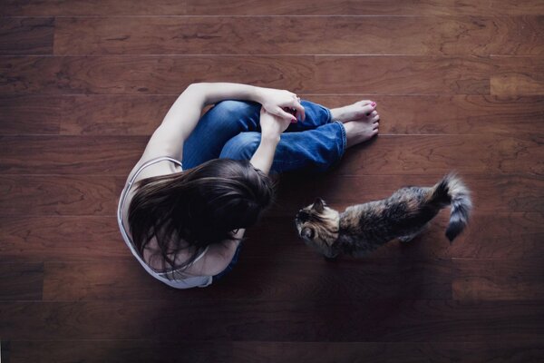 A girl is sitting on the floor with a cat