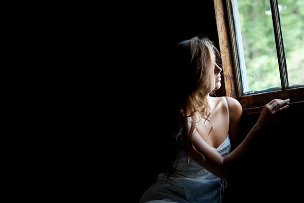 Ragazza carina guardando fuori dalla finestra