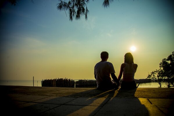 Pareja de enamorados en el fondo de la puesta de sol en la orilla del lago