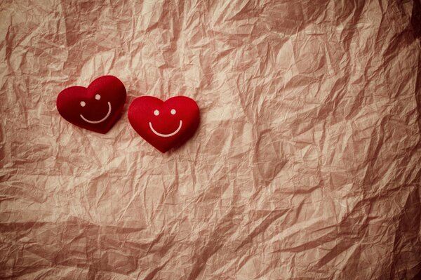 Zwei rote Smiley-Herzen liegen auf zerknittertem Papier