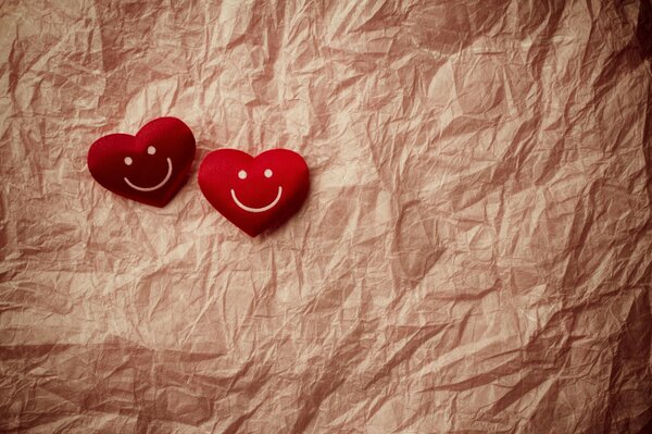 Two red smiley hearts lying on crumpled paper