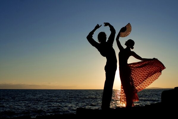 Silhouette d un gars et une fille dans une robe avec un ventilateur Stay dans une pose de danse