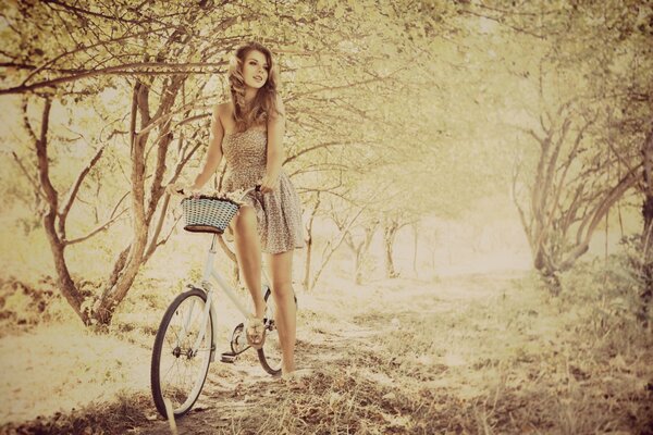 Девушка в светлом платье на велосипеде с корзинкой