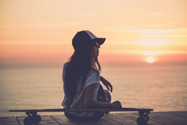 A girl in a cap by the seashore at sunset