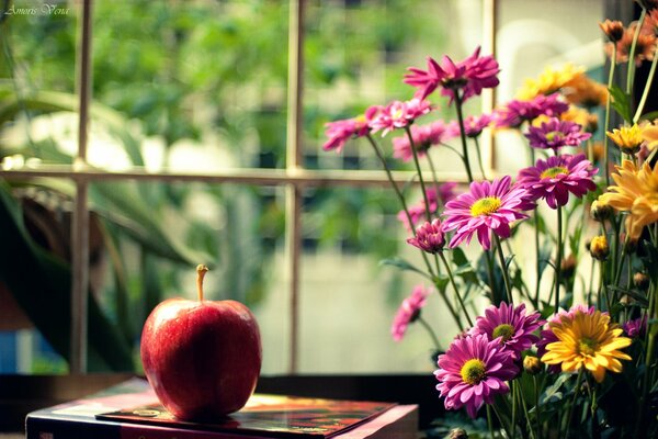 Deliciosa manzana roja con un ramo de flores