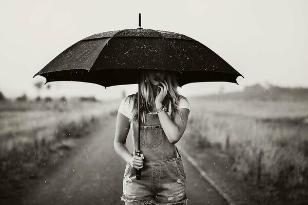 E piove e una ragazza sulla strada con un ombrello
