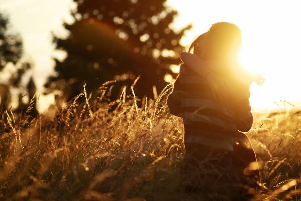 A couple in love, a man and a woman in an embrace in a field against the background of the setting sun