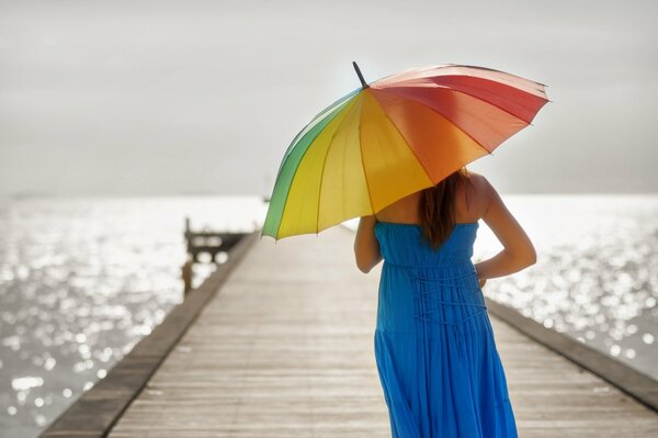 Chica en el muelle con un paraguas de color