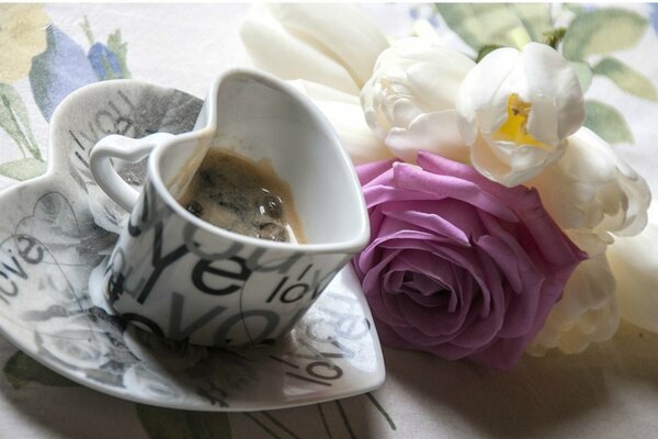 Taza de café con ramo de rosas en la mesa