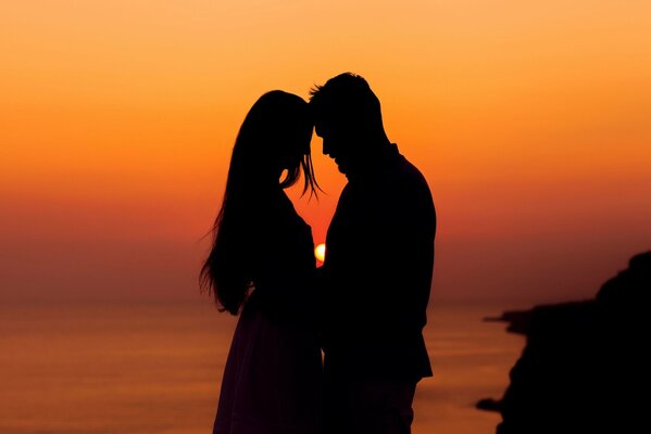 A couple in love romantically poses at sunset