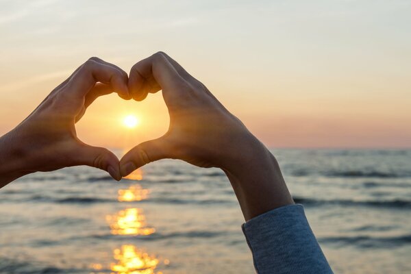 Sonne im Herzen aus der Hand über dem Meer