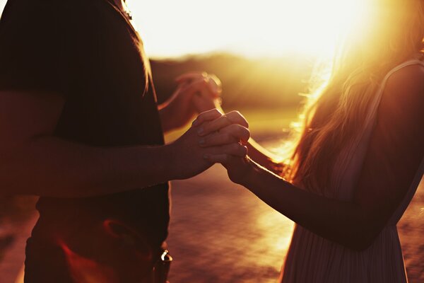 Dos amantes tomados de la mano en medio de la puesta de sol