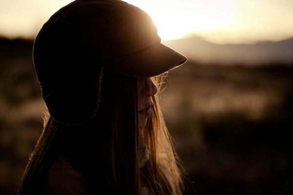 A girl in a hat at sunset , a field