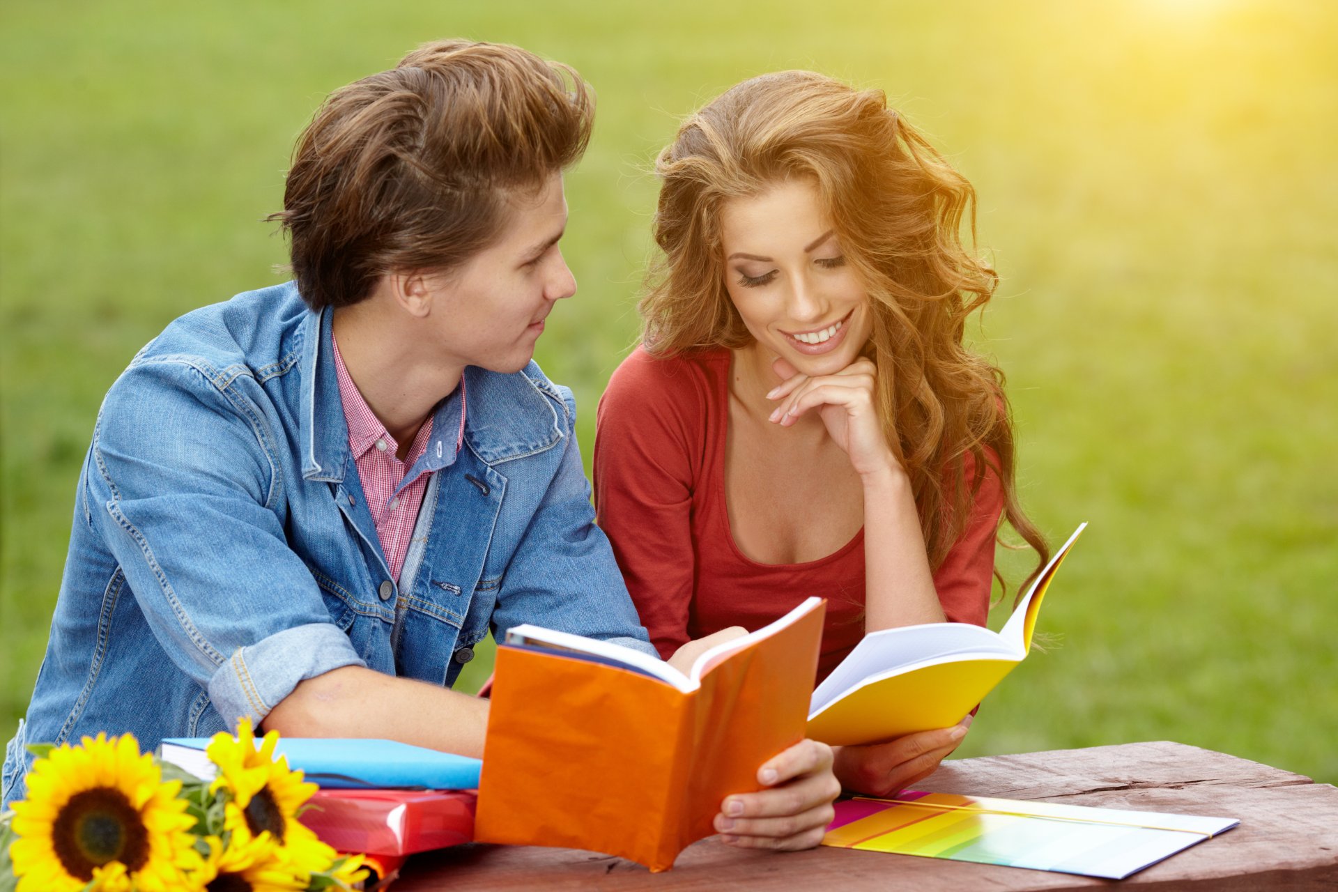 mädchen braunhaarige locken freund lächeln notizbücher gras park sonniger tag sonnenblumen