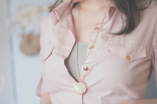 Fille en blouse rose clair. Pendentif en forme de coeur