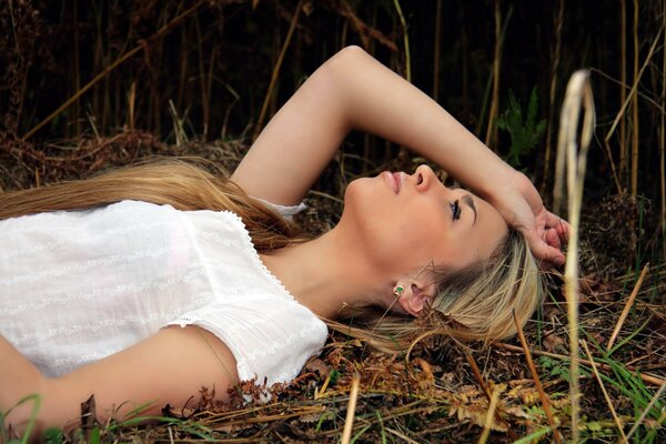 The girl is lying on the field in the grass