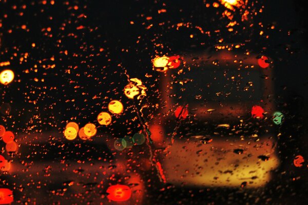 The lights of the evening city through the drops on the glass