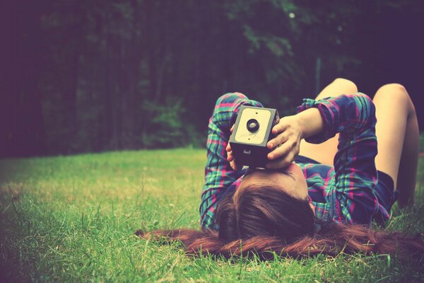 A girl with a camera on the green grass