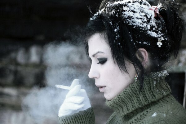 The brunette smokes in the cold in winter. Cigarette smoke