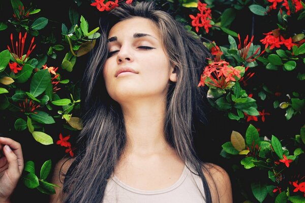 A brunette girl lies on a green background with flowers