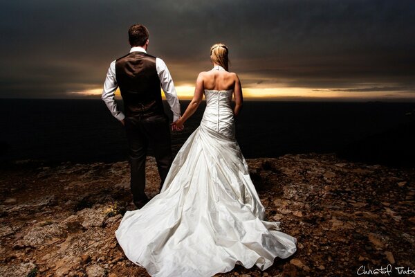 Chica en vestido de novia con novio de la mano