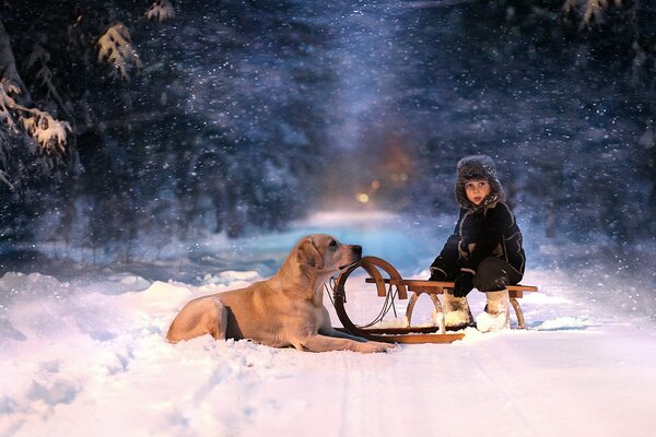 Ein Kind auf einem Schlitten mit einem Hund im Schnee