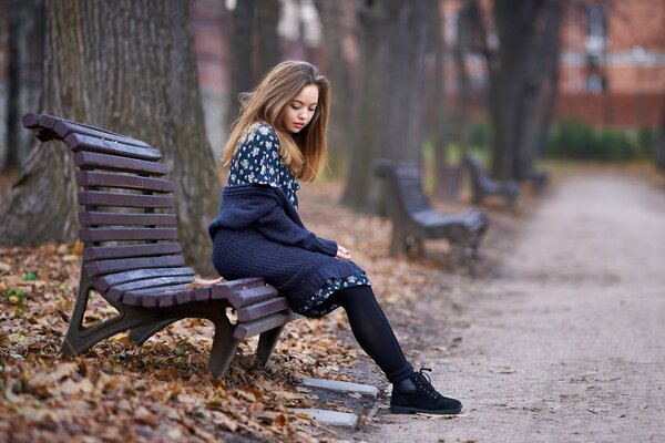 Parque de otoño. Chica pensativa en el banco