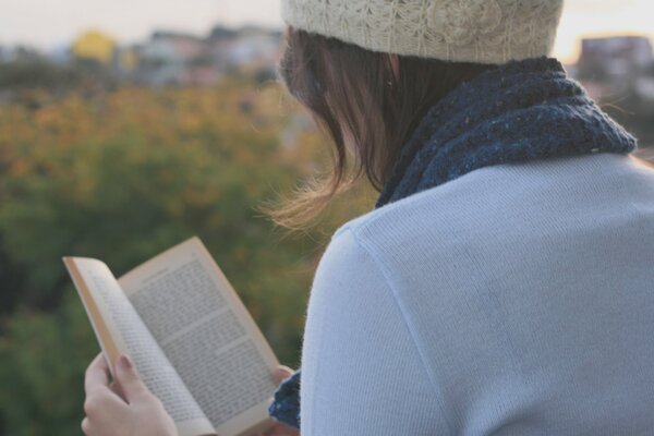 Brunette girl reading a book in the park
