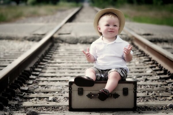 Naughty boy sitting on a suitcase