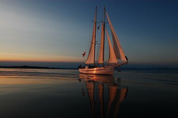 Ein Segelboot in der Nacht. Segelboot auf dem Meer bei Sonnenuntergang