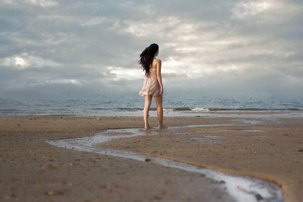 Chica a lo largo de la orilla del mar