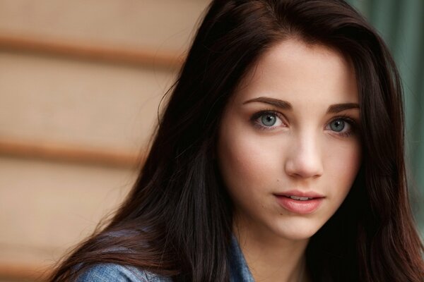 A beautiful blue-eyed brown-haired woman looks into the camera