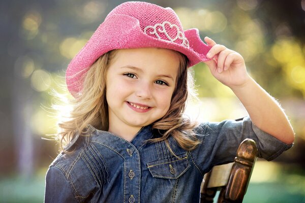 Cute smiling girl in a denim shirt and pink cowboy hat