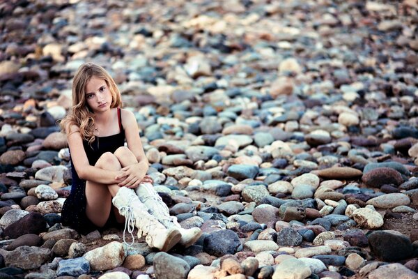 A serious girl is sitting on the rocks