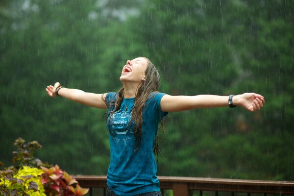 Chica joven disfruta de la lluvia