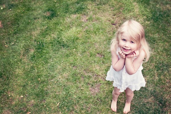 A girl with an angelic smile on the background of grass