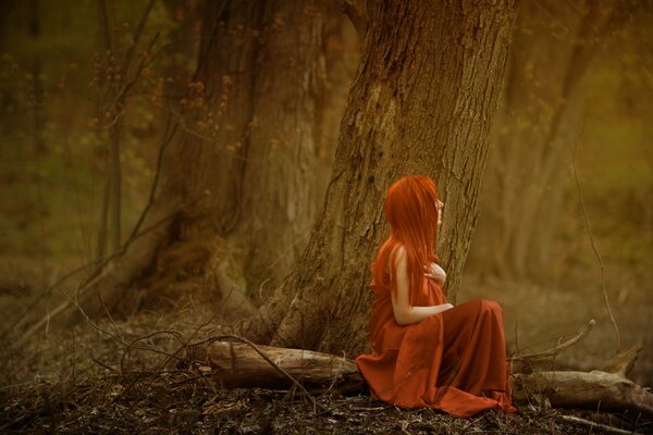 Pelirroja chica sentada en el bosque