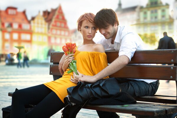 Fille Rousse dans une robe jaune avec des tulipes dans les mains sur un banc