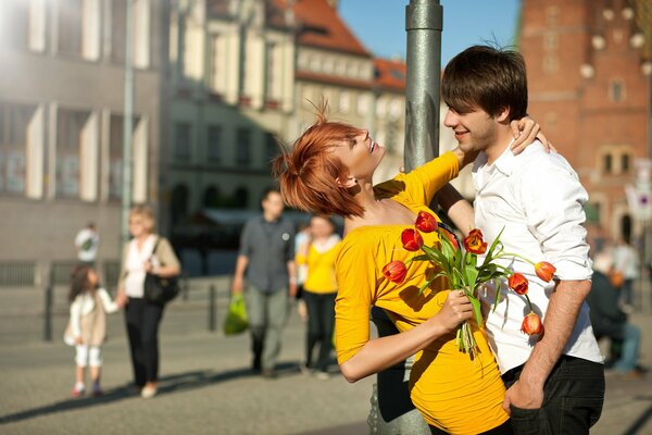 A red-haired girl in a yellow dress with tulips in her hand