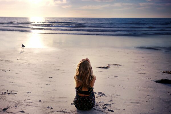 The girl is sitting alone on the seashore