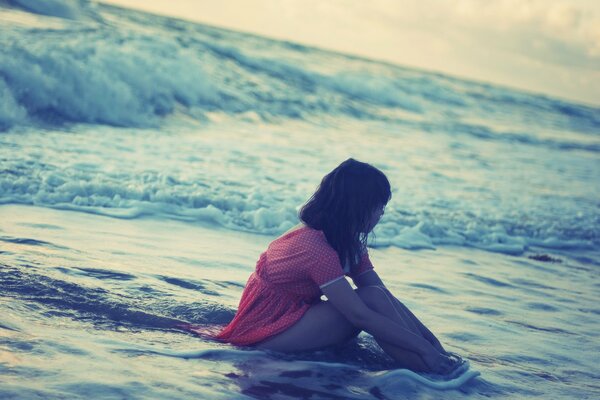 La ragazza si siede nel mare e gode dell acqua di mare