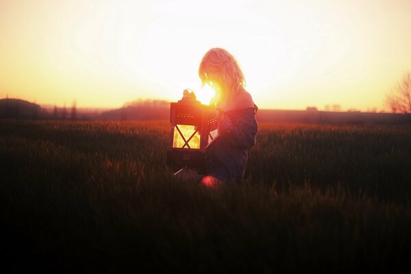 Mädchen im Feld mit Lampe bei Sonnenuntergang