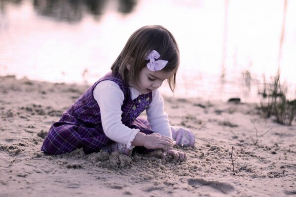 Una niña construye una ciudad de arena