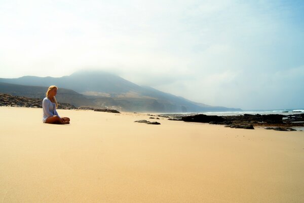 Dziewczyna siedzi sama na piaszczystej plaży