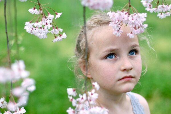 Sad little girl in a blooming garden