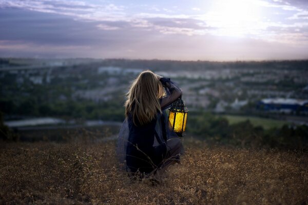 A girl with a lantern on the bank of a cliff