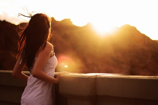 Mädchen im weißen Kleid schaut auf den Sonnenuntergang