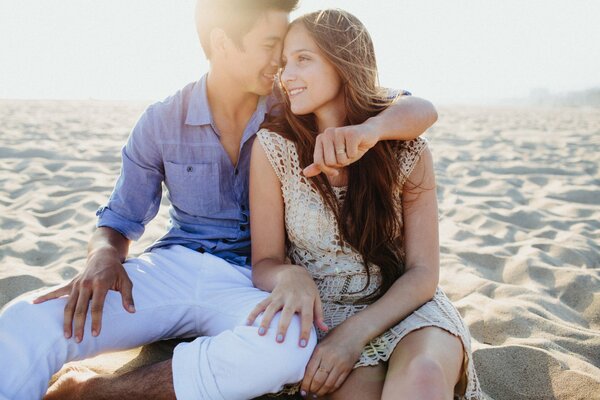 A guy and a girl are sitting on the sand