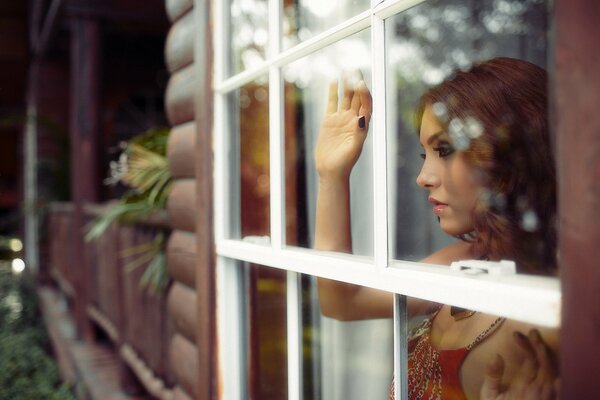 Belle fille réfléchie regarde par la fenêtre