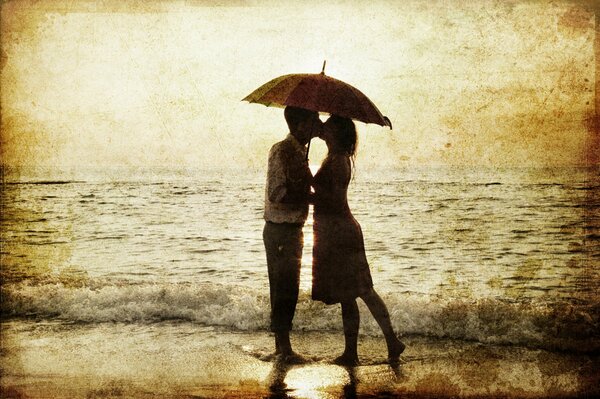 A couple of lovers on the sea beach kissing under an umbrella